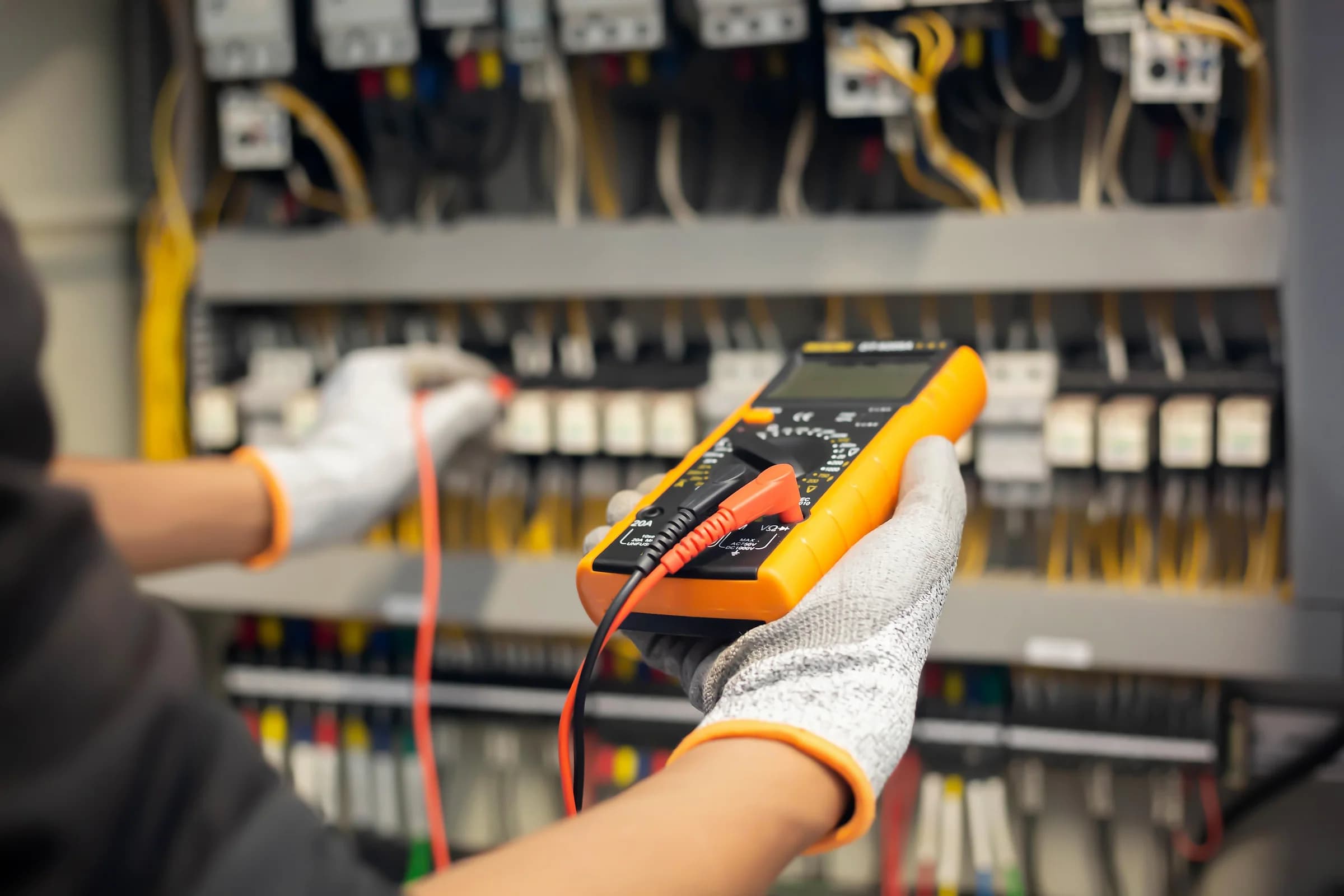 Ein Elektriker prüft, mit einem Messgerät, die Sicherungen in einem Sicherungskasten.
